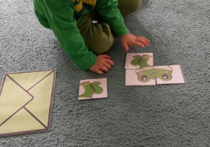 Chłopiec układa puzzle przedstawiające żabę