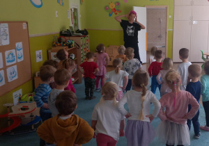 Dzieci stoją naprzeciwko prowadzącej i tańczą