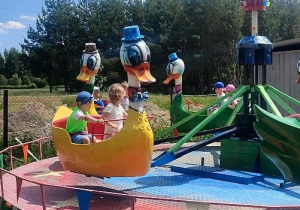 Dzieci siedzą na karuzeli w kształcie kaczora.