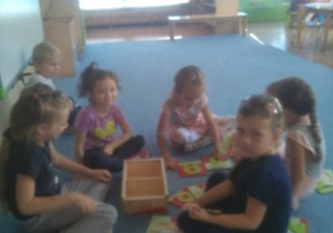 Dzieci bawią się uzupełniając drewniane cyferki na dywanie