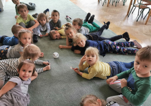 Dzieci leżą na dywanie i słuchają muzyki