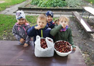 Dzieci w ogrodzie z torbą i koszem kasztanów