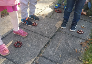 Dzieci układają figury z kasztanów w ogrodzie