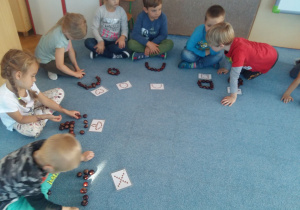 Dzieci na dywanie odwzorowują figury z kasztanów