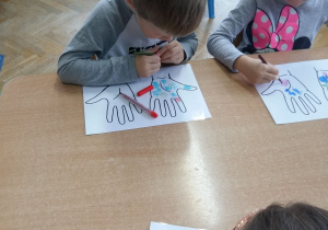 Dzieci rysują mazakami bakterie na obrazkach dłoni