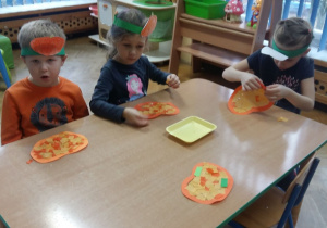 Dzieci tworzą papierowe dynie przy stoliku