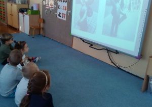 Dzieci oglądają prezentację o misiach na dywanie