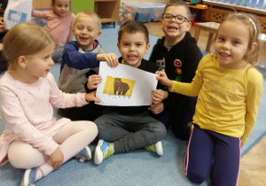 Grupa dzieci pokazuje ułożony obrazek przedstawiający niedźwiedzia