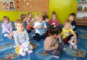 Dzieci siedzą na dywanie ze swoimi pluszowymi przyjaciółmi