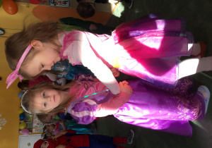 Dwie dziewczynki przebrane za jednorożca i księżniczkę tańczą w kółeczku